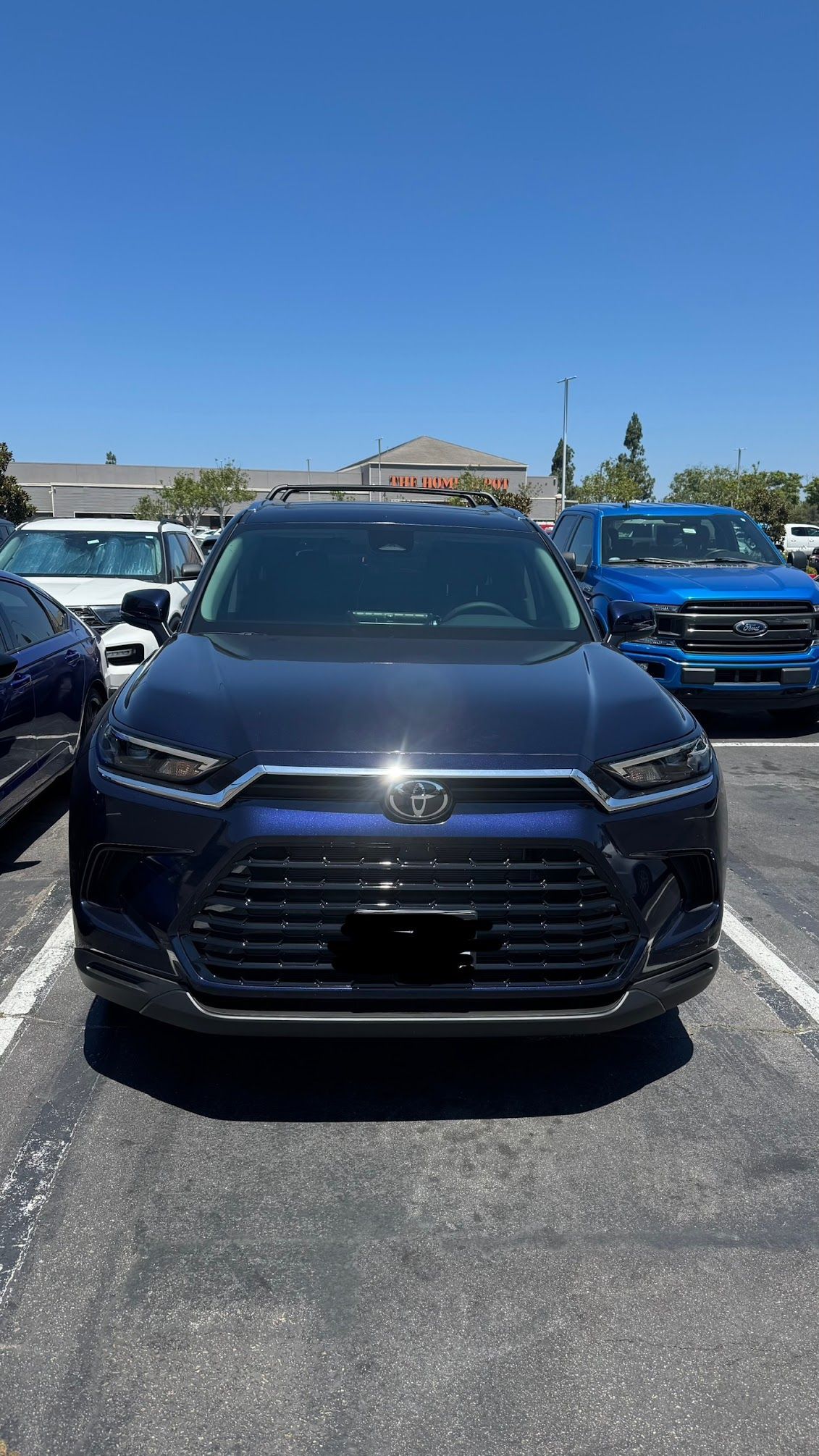 Dark blue SUV parked in a lot with a clear sky, other vehicles visible in the background.