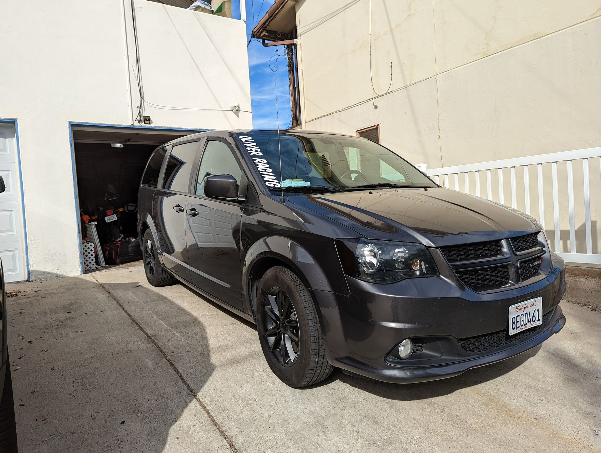 Dark gray Dodge Grand Caravan parked in driveway with an open garage.