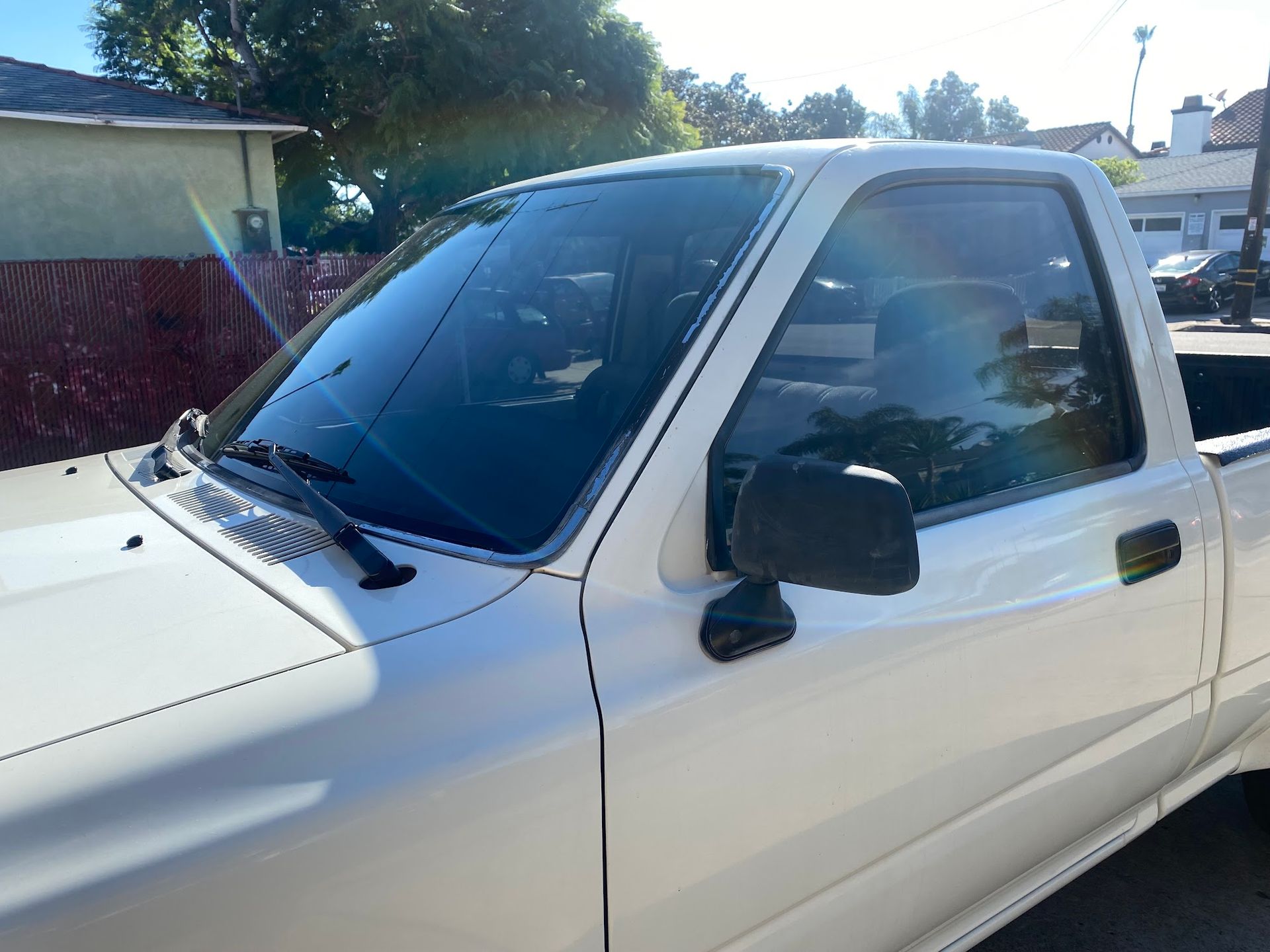 White Toyota pickup truck parked on a sunny street.