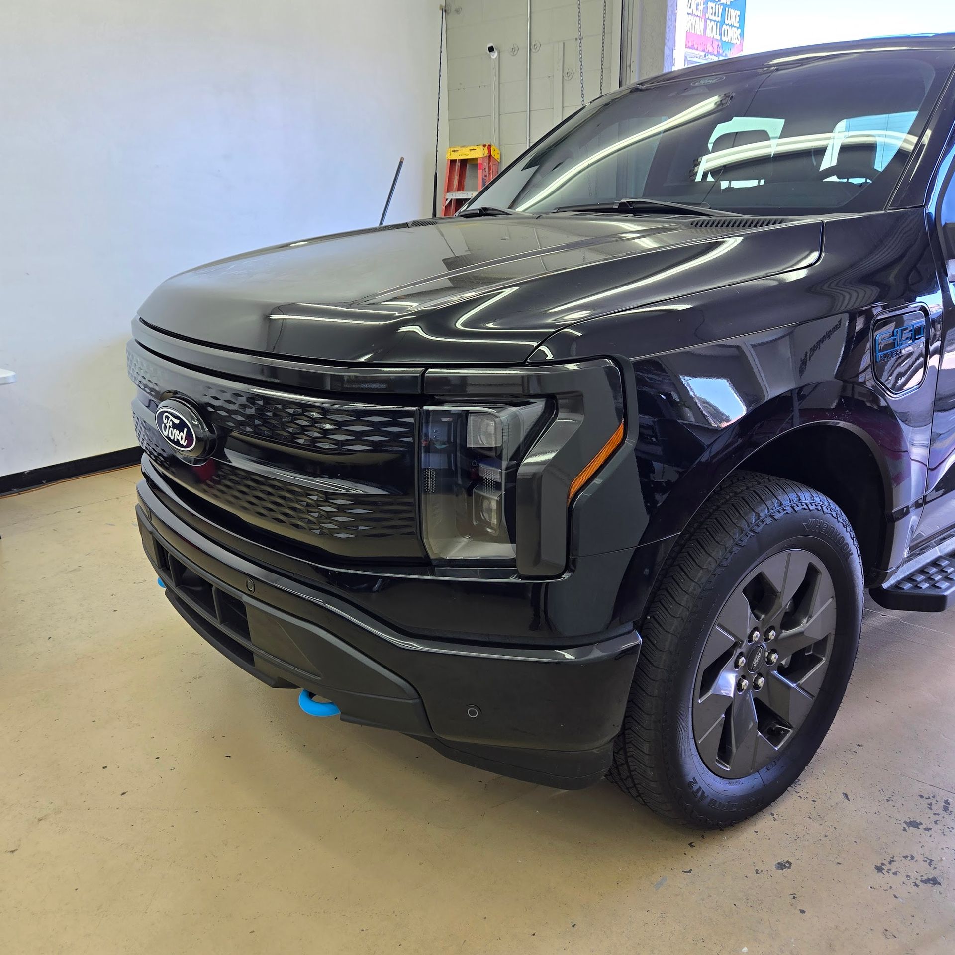 Black Ford F-150 Lightning electric truck parked indoors, showing the front, with black grille and headlights.
