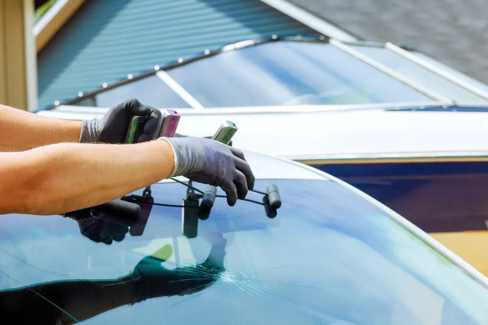 Person in gloves repairing cracked windshield.