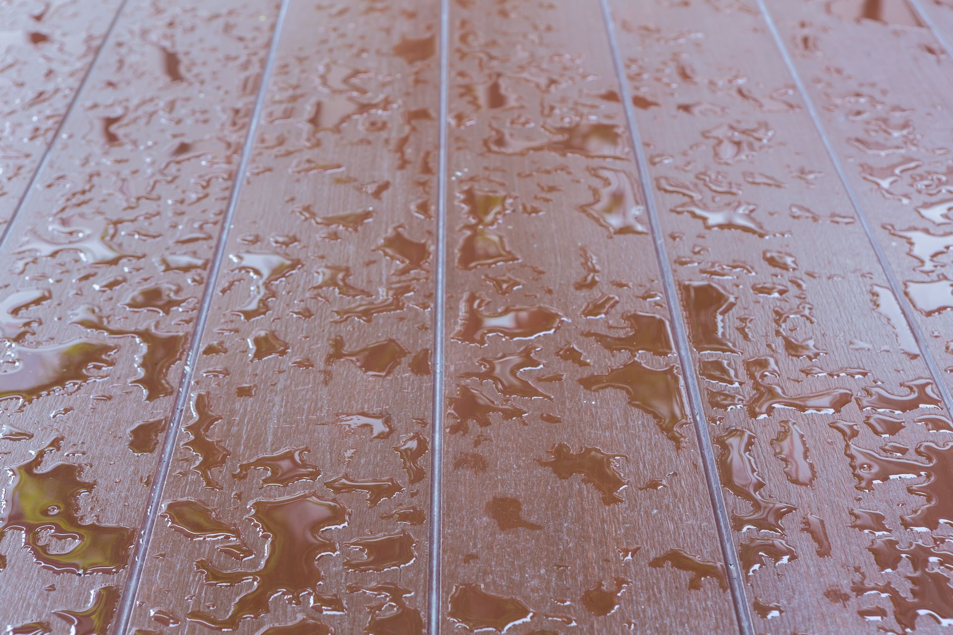 A close up of a wooden floor with water drops on it.