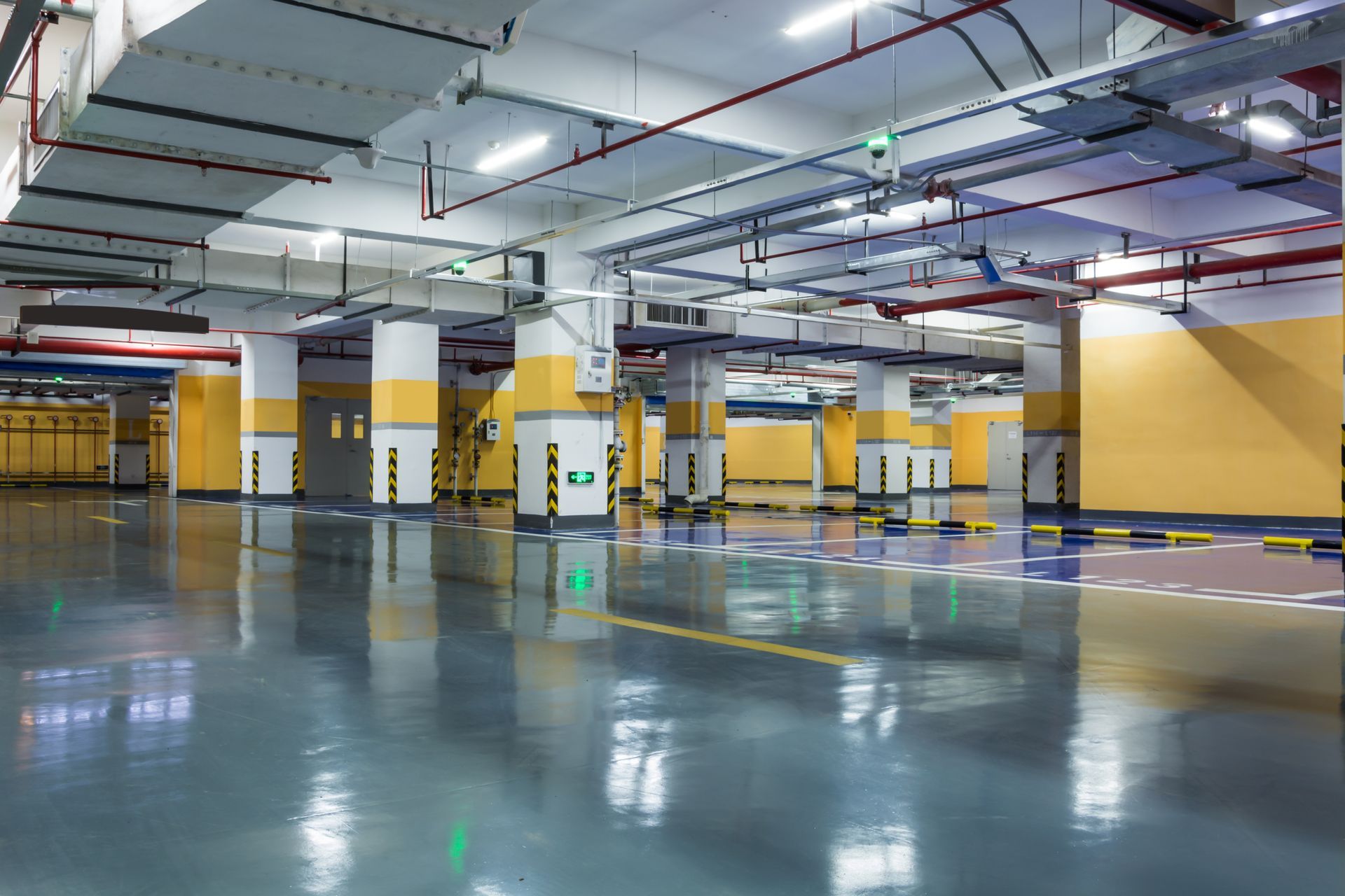 An empty underground parking garage with a shiny floor.