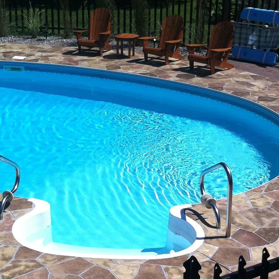 A swimming pool surrounded by chairs and a fence