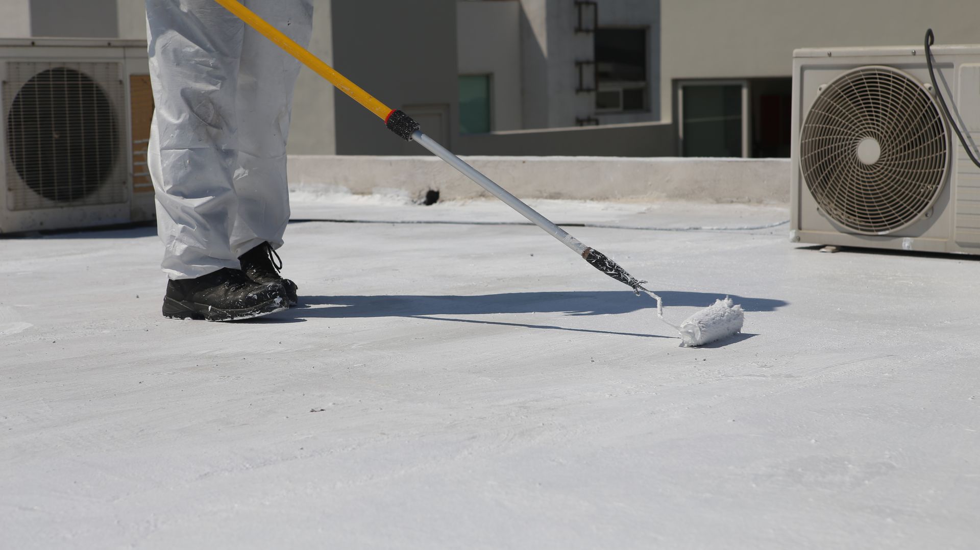 A person is painting a roof with a roller.