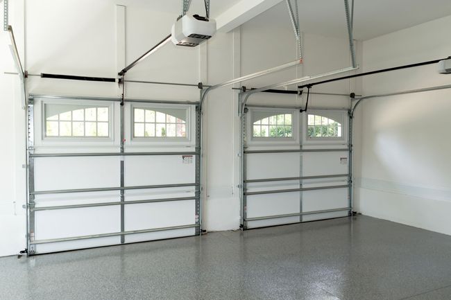 An empty garage with two garage doors and a lift.