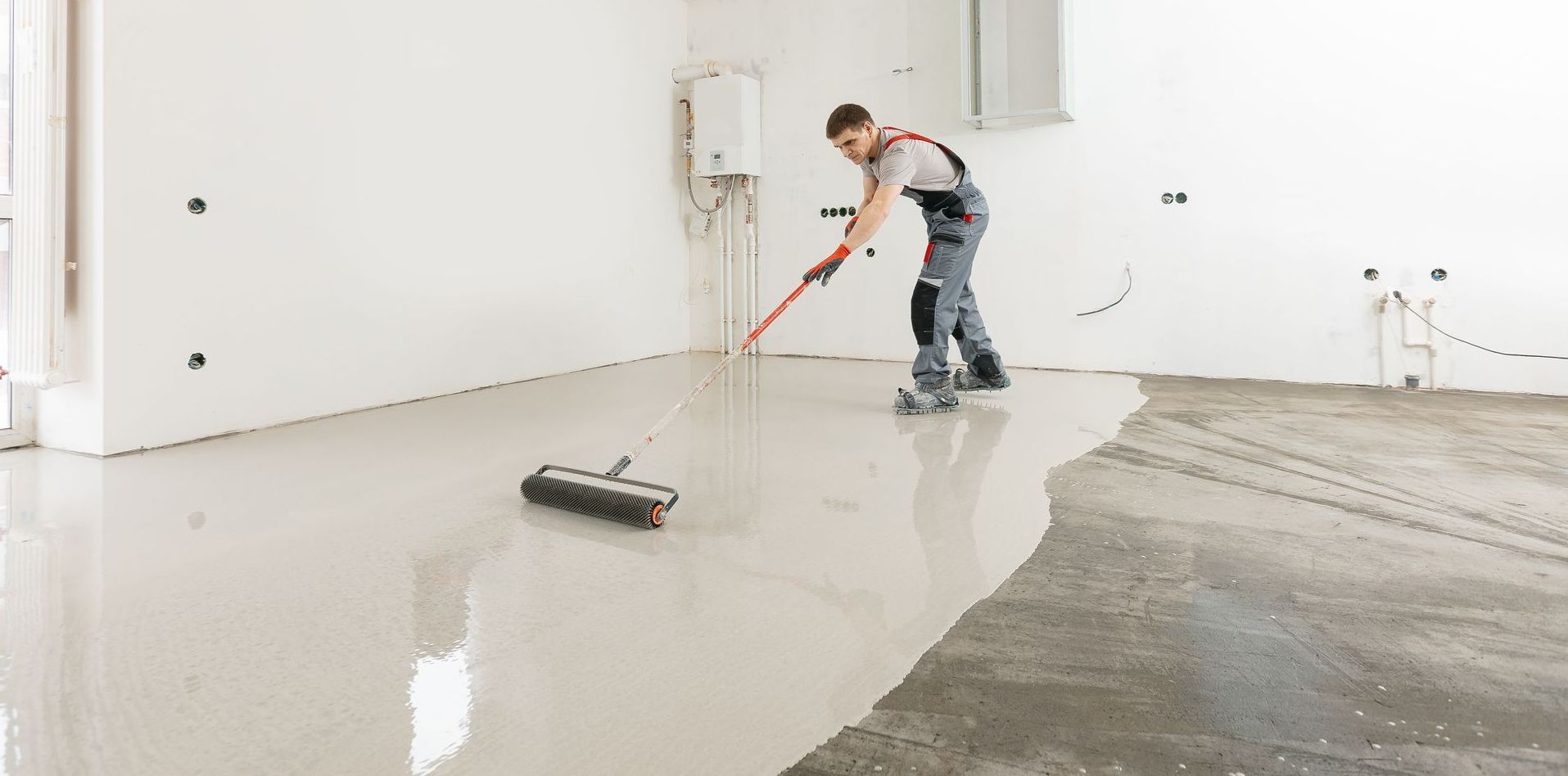 A man is painting a floor with a broom.