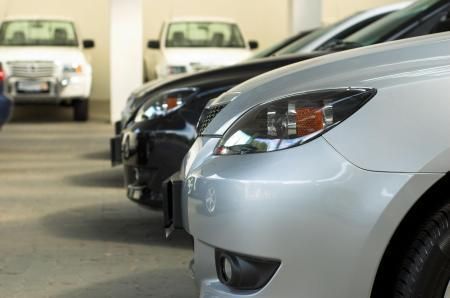 A line of parked cars in an indoor garage, with a silver vehicle prominently featured in the foreground.