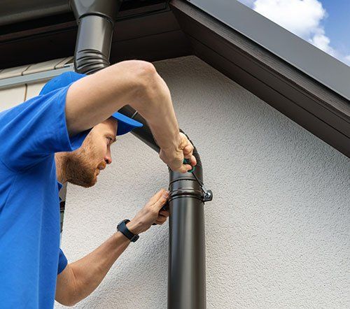 Worker installing house roof gutter