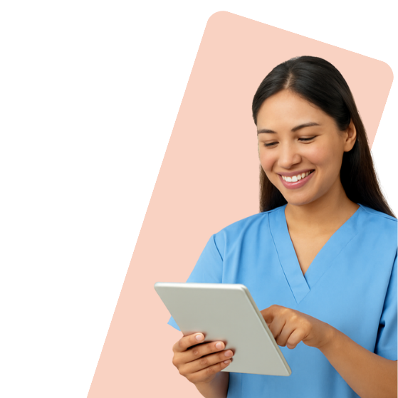 Smiling nurse in blue scrubs using a tablet, set against a peach-colored background.