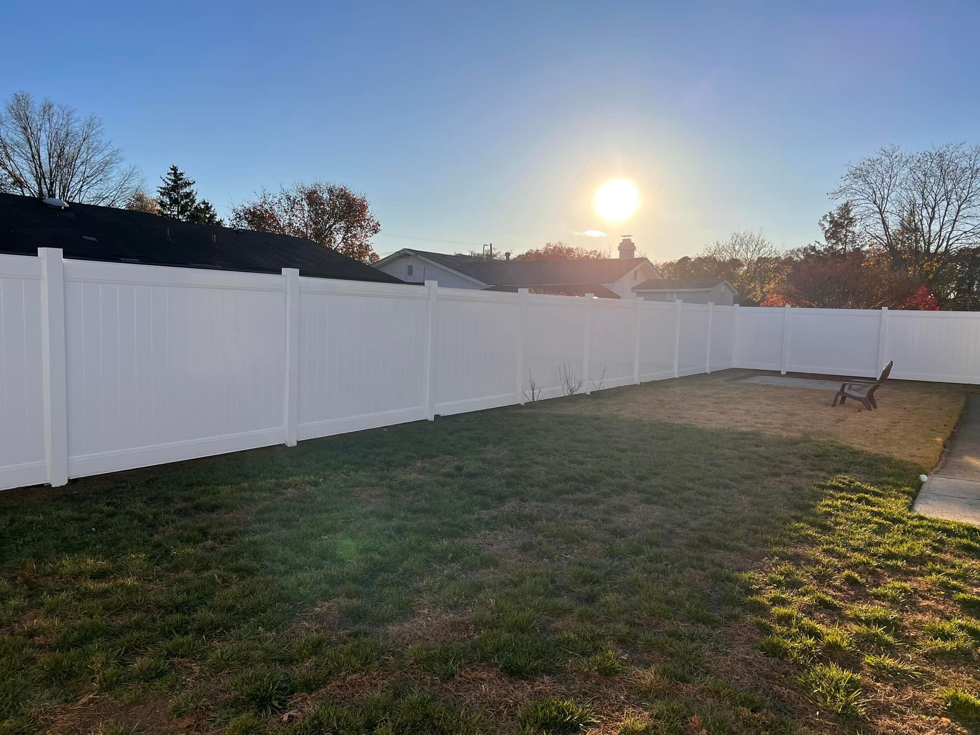 A white fence surrounds a lush green yard.