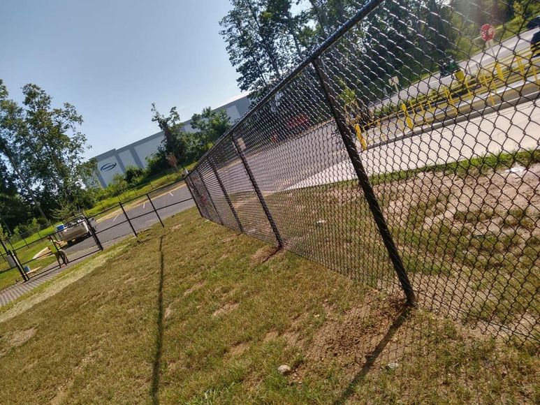 A chain link fence is sitting in the middle of a grassy field.