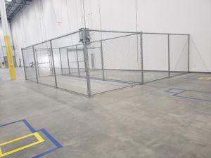 There is a chain link fence in the middle of a warehouse.