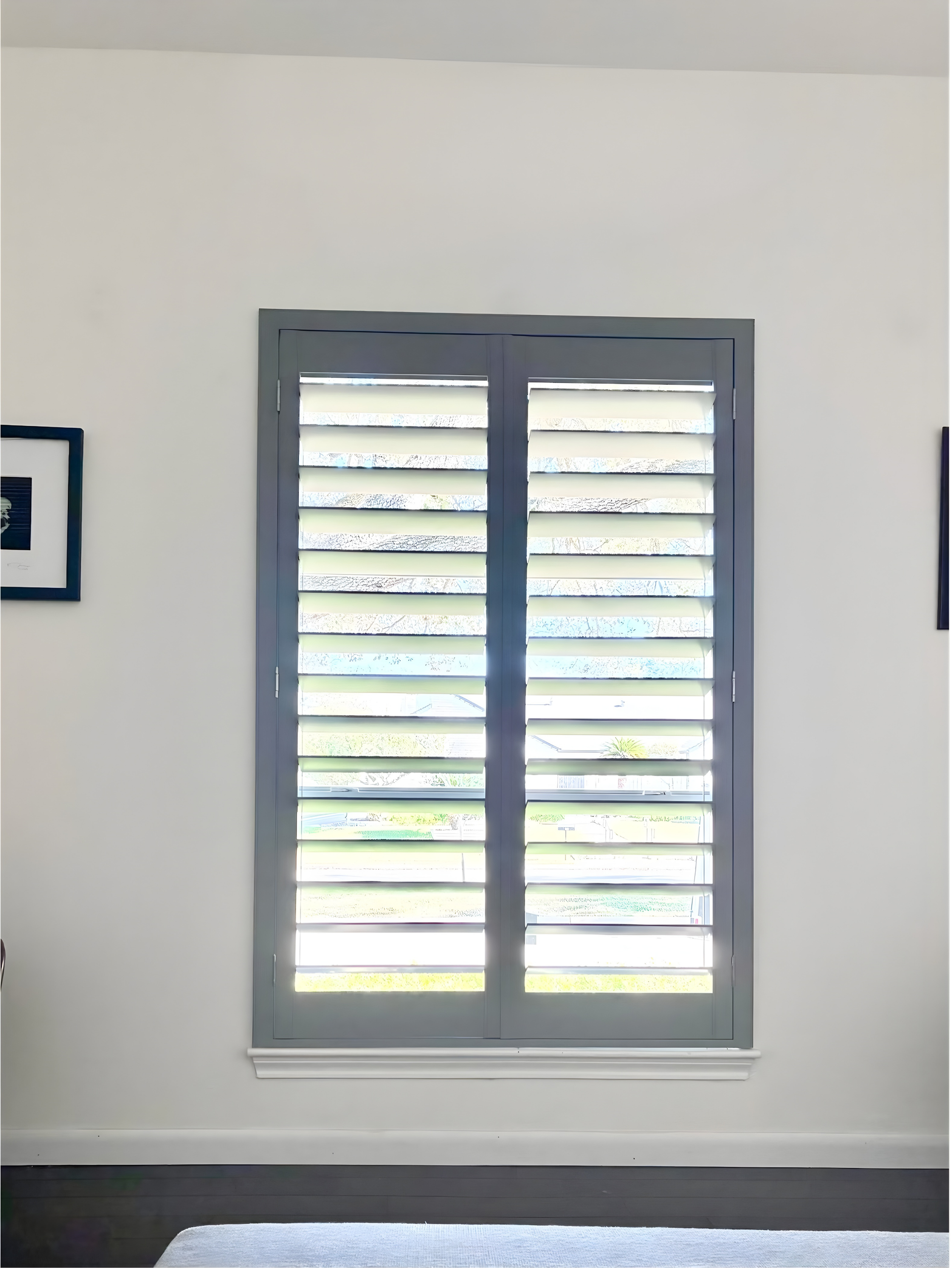 Gray shutters on a white wall, with a small black frame to the left.