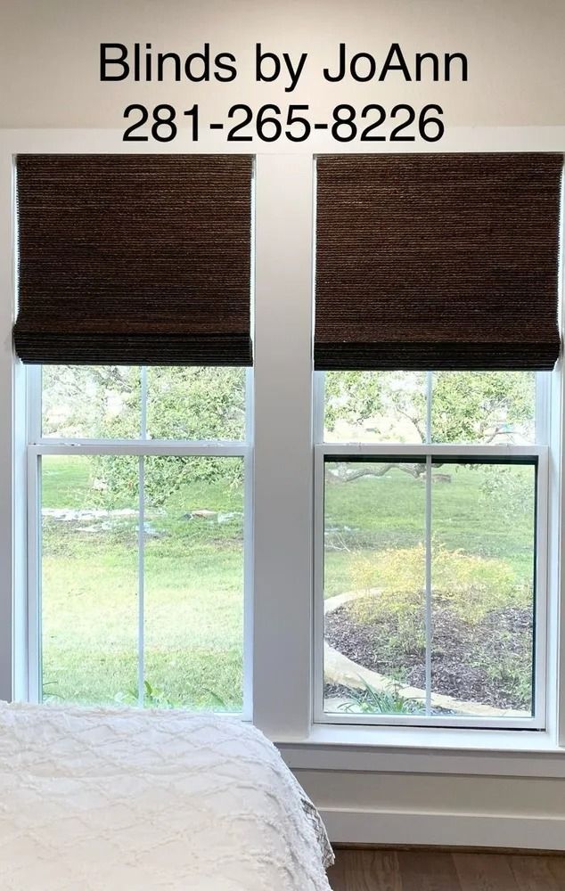 Two windows with brown woven blinds, white trim, and a bed in front. Phone number listed.