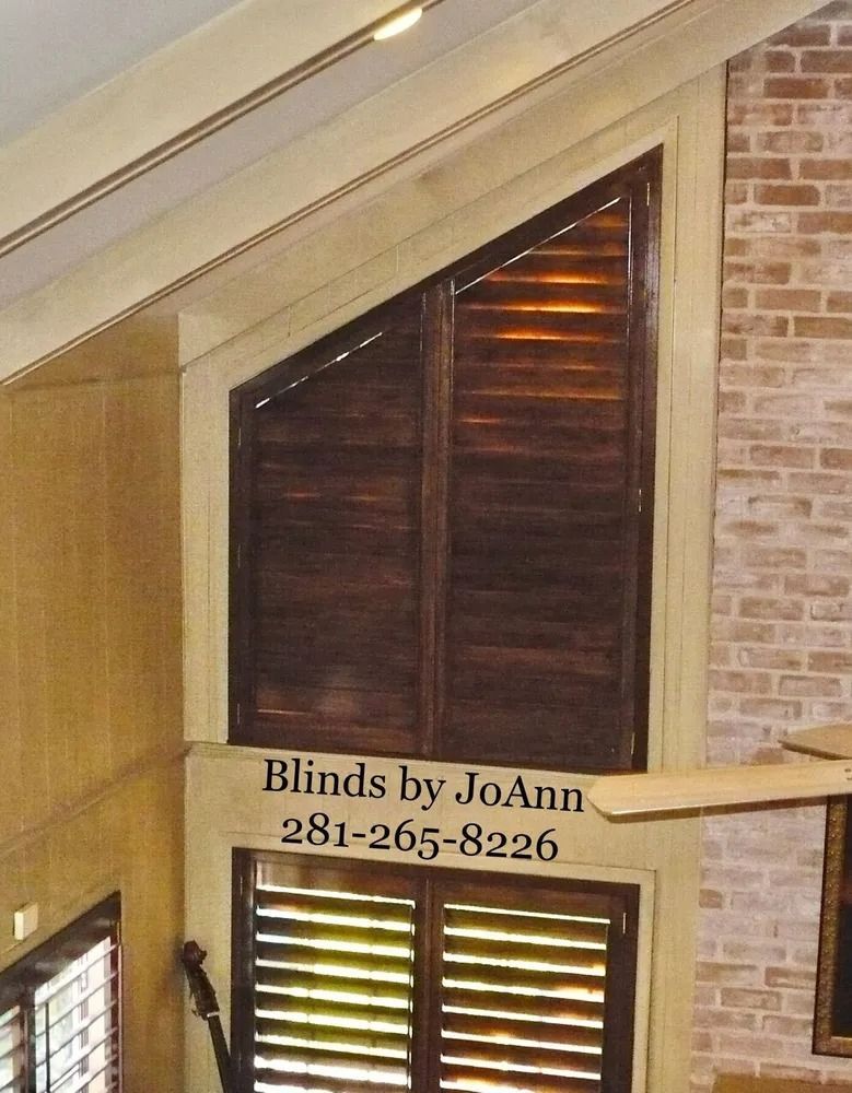 Angled wooden shutters in a window, brick wall, and the text 