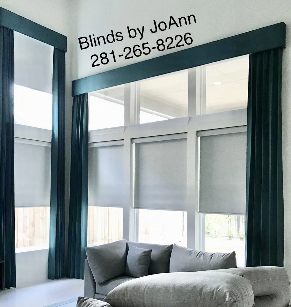 Living room with large windows, teal curtains and header, gray shades, and a gray sofa. 