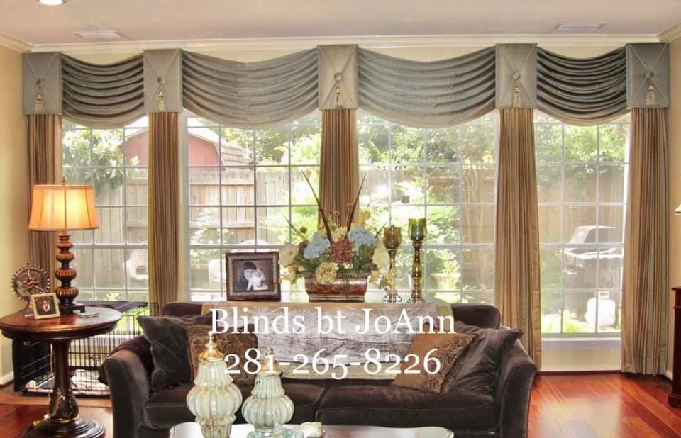 Living room with window, sofa, table, ornate window treatments in blue and tan.