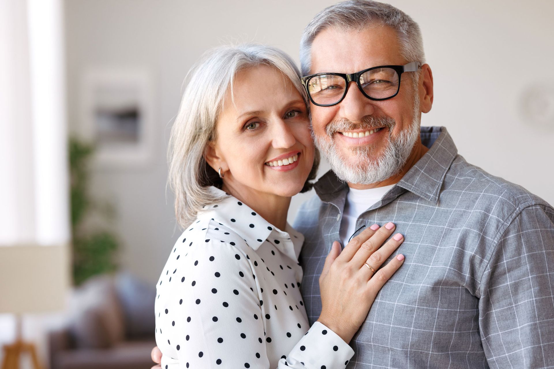 A man and a woman are hugging each other and smiling for the camera.