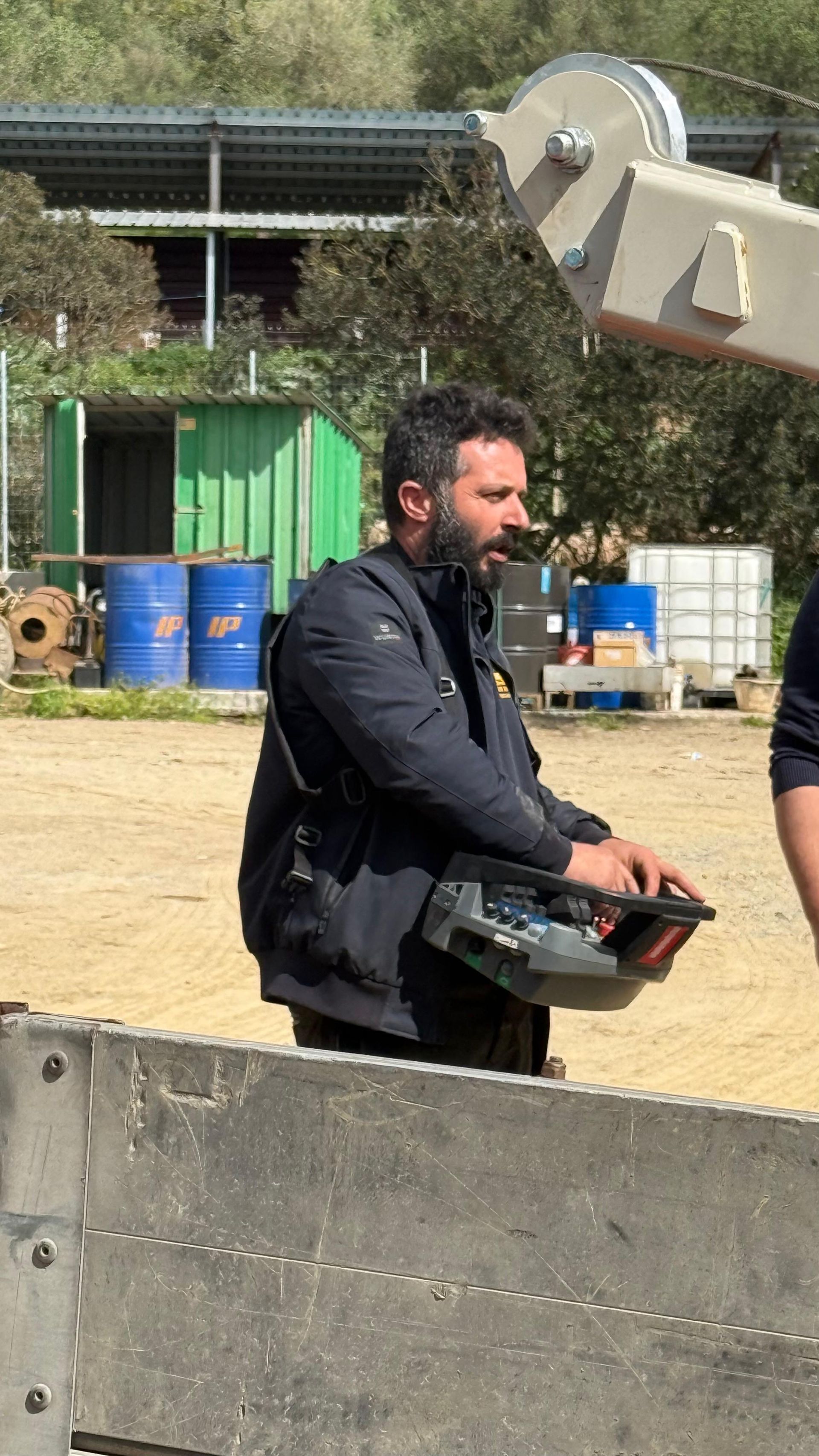 Piattaforma di perforazione in un cantiere con tubi blu, colline verdi e un cielo azzurro brillante.