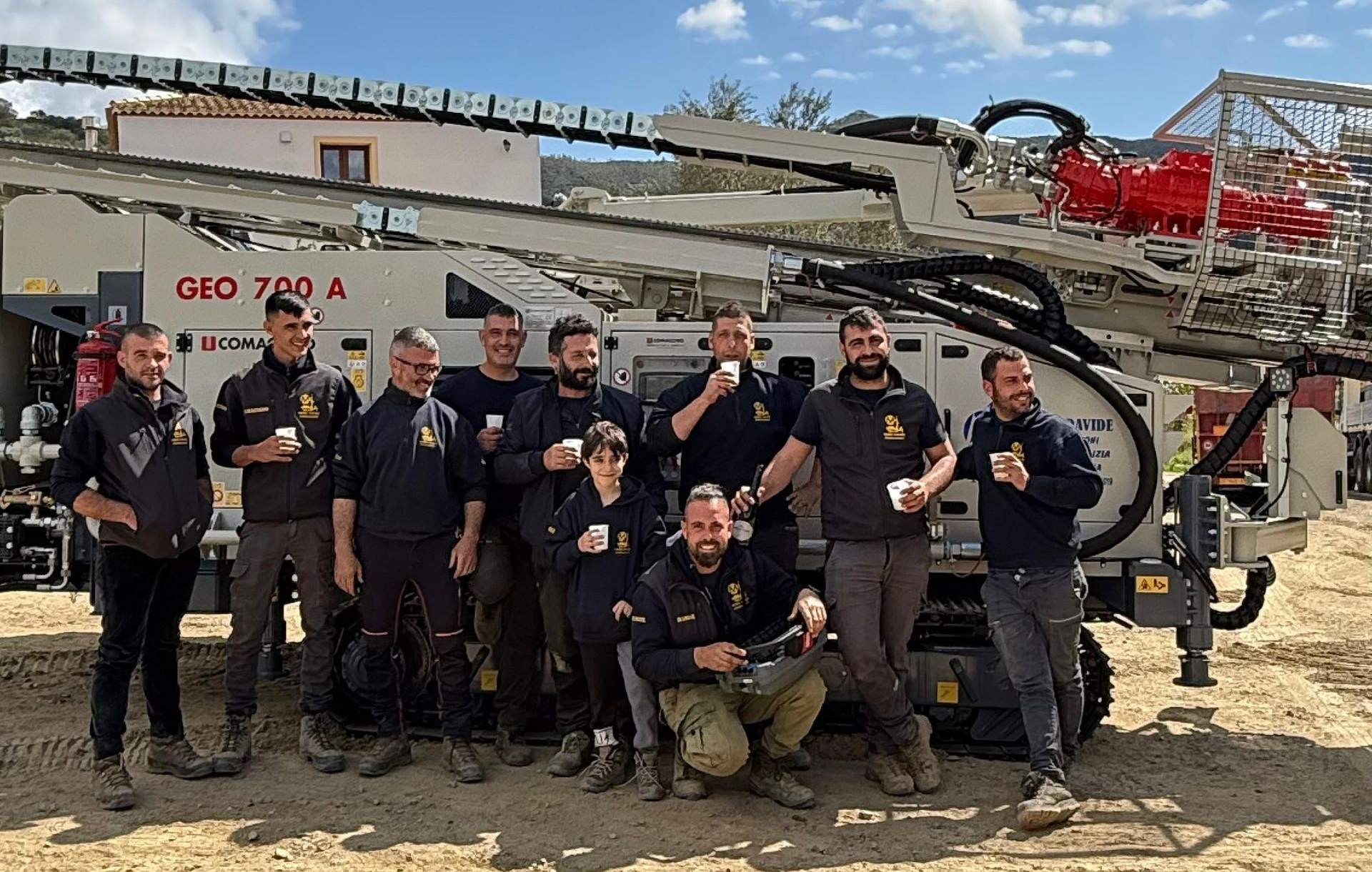 Un gruppo di operai in uniforme nera posa con una macchina GEO 700 A in un ambiente esterno.