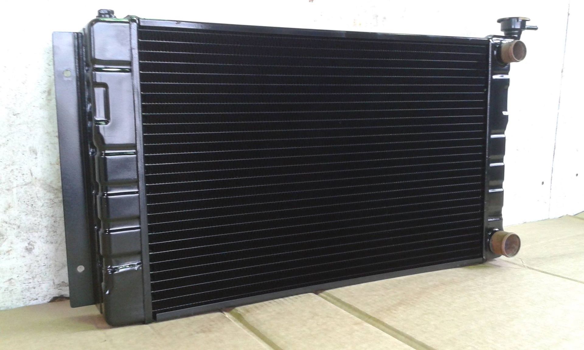Black car radiator on a cardboard surface.