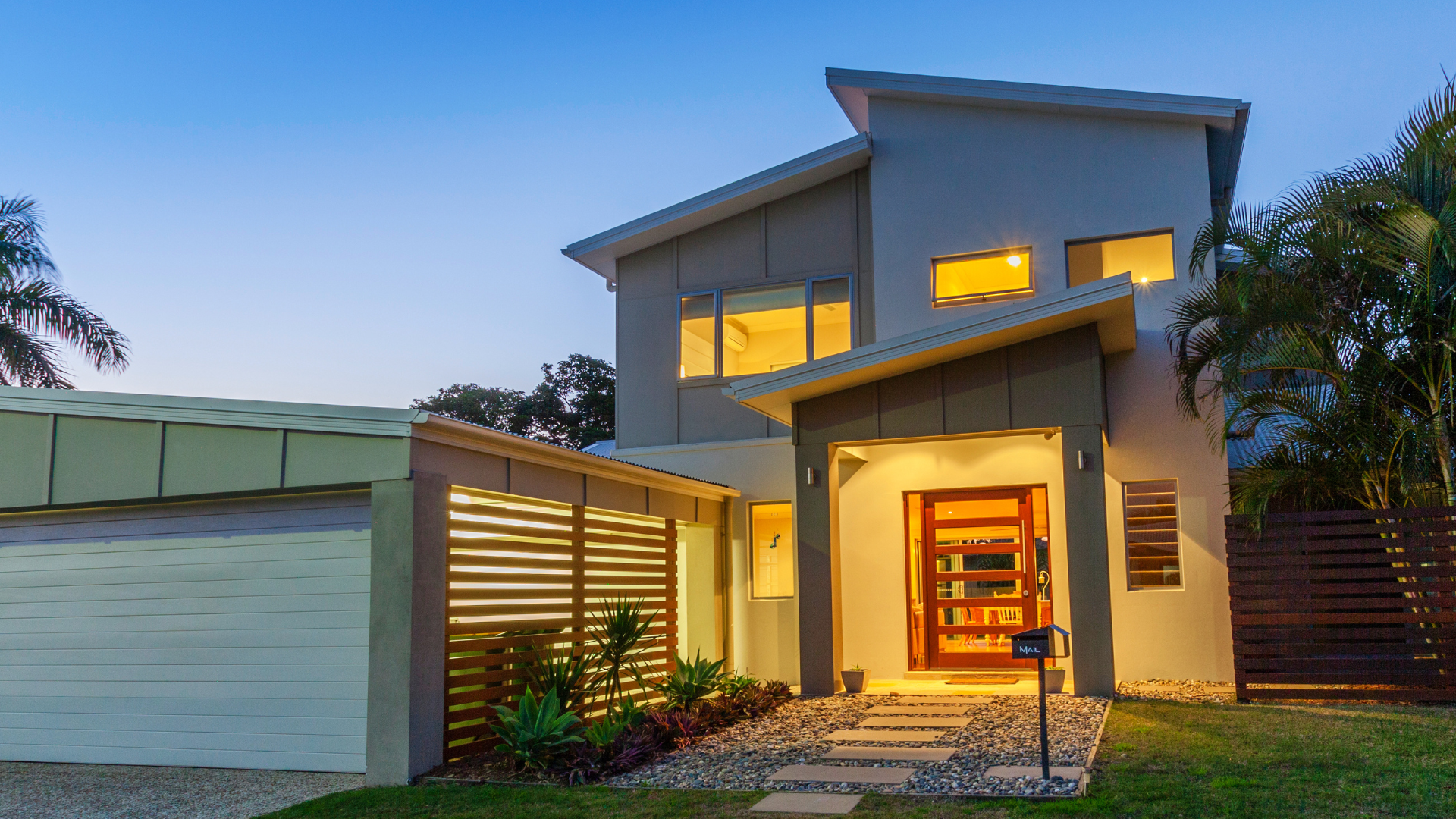 A large house with a lot of windows and a garage is lit up at night.