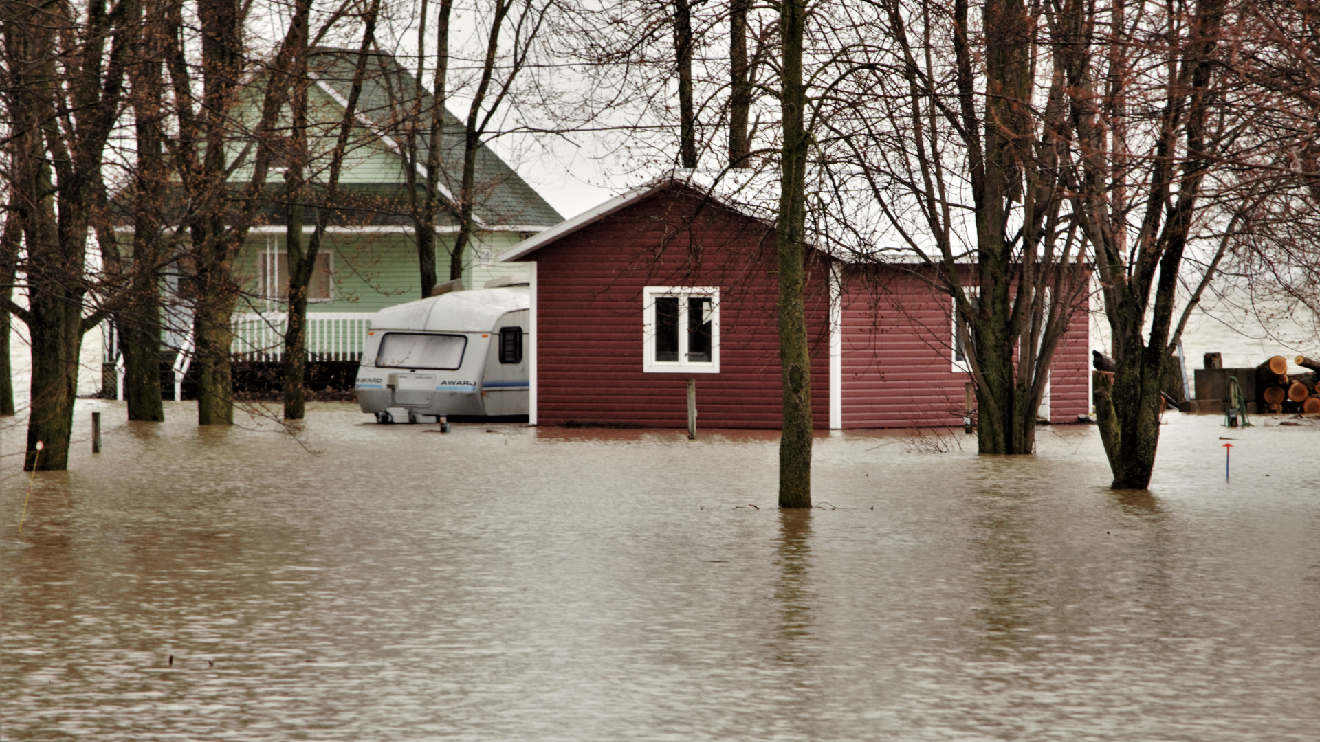 A house and a trailer are surrounded by flood water.