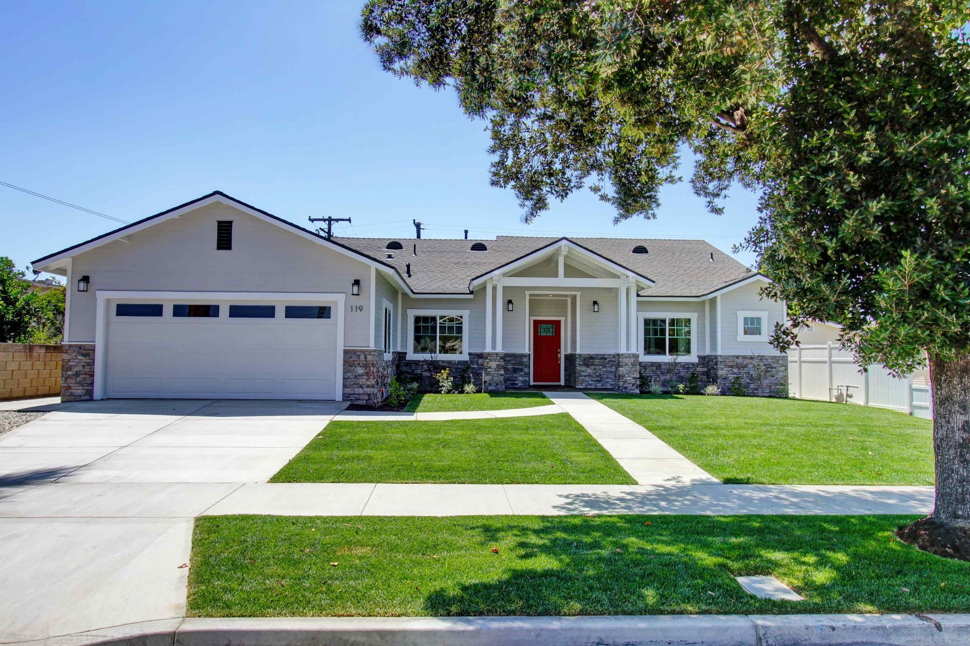 White house with black trim and patio, lush green lawn.