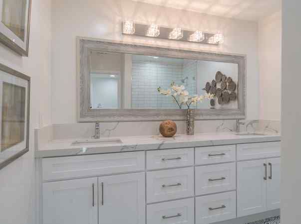 White bathroom with a double vanity, large mirror, and floral decor.