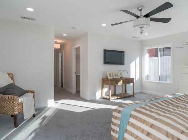 Bedroom with gray carpet, a bed, a TV, a desk, and a chair.
