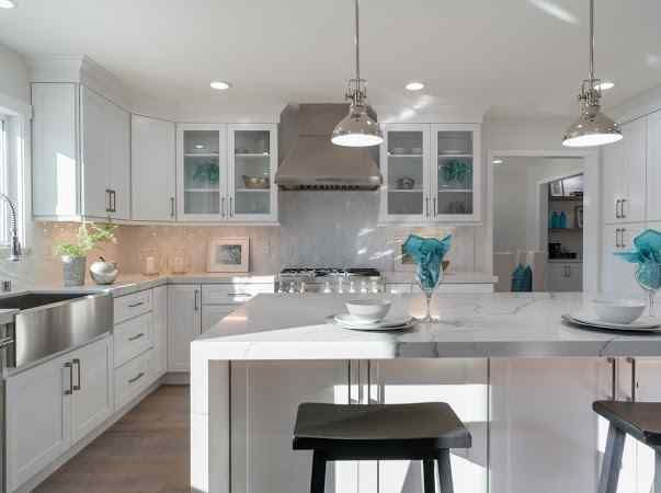 White kitchen with island, cabinets, and stainless steel appliances; natural light.