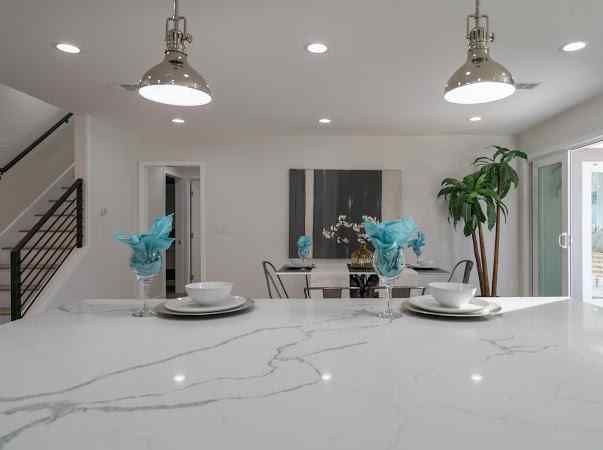 White kitchen with quartz countertop, pendant lights, and dining area.