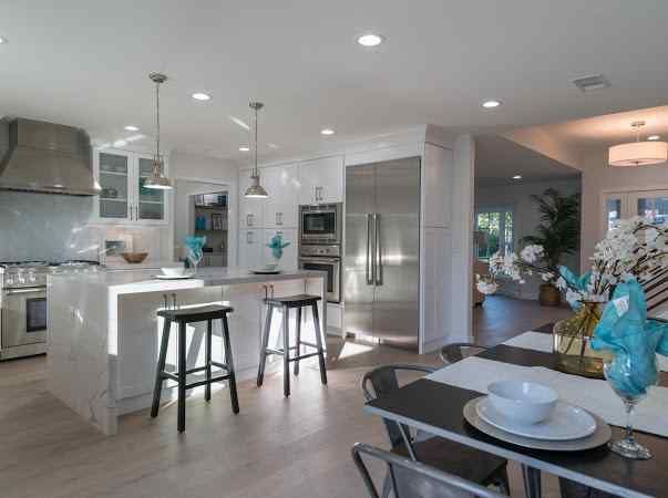 Bright, modern kitchen with white cabinets, stainless steel appliances, and a dining area.