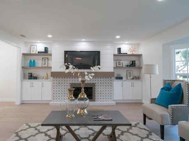 Living room with fireplace, built-ins, TV, and seating. Gray, white, and blue color scheme.