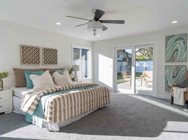 Spacious bedroom with gray carpet, king-sized bed, and sliding glass door to the backyard.