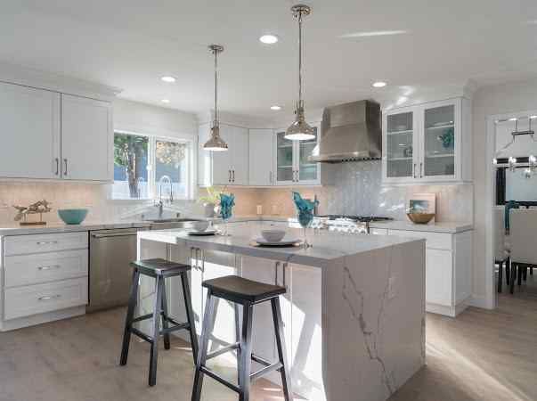Bright white kitchen with island, white cabinets, and stainless steel appliances.
