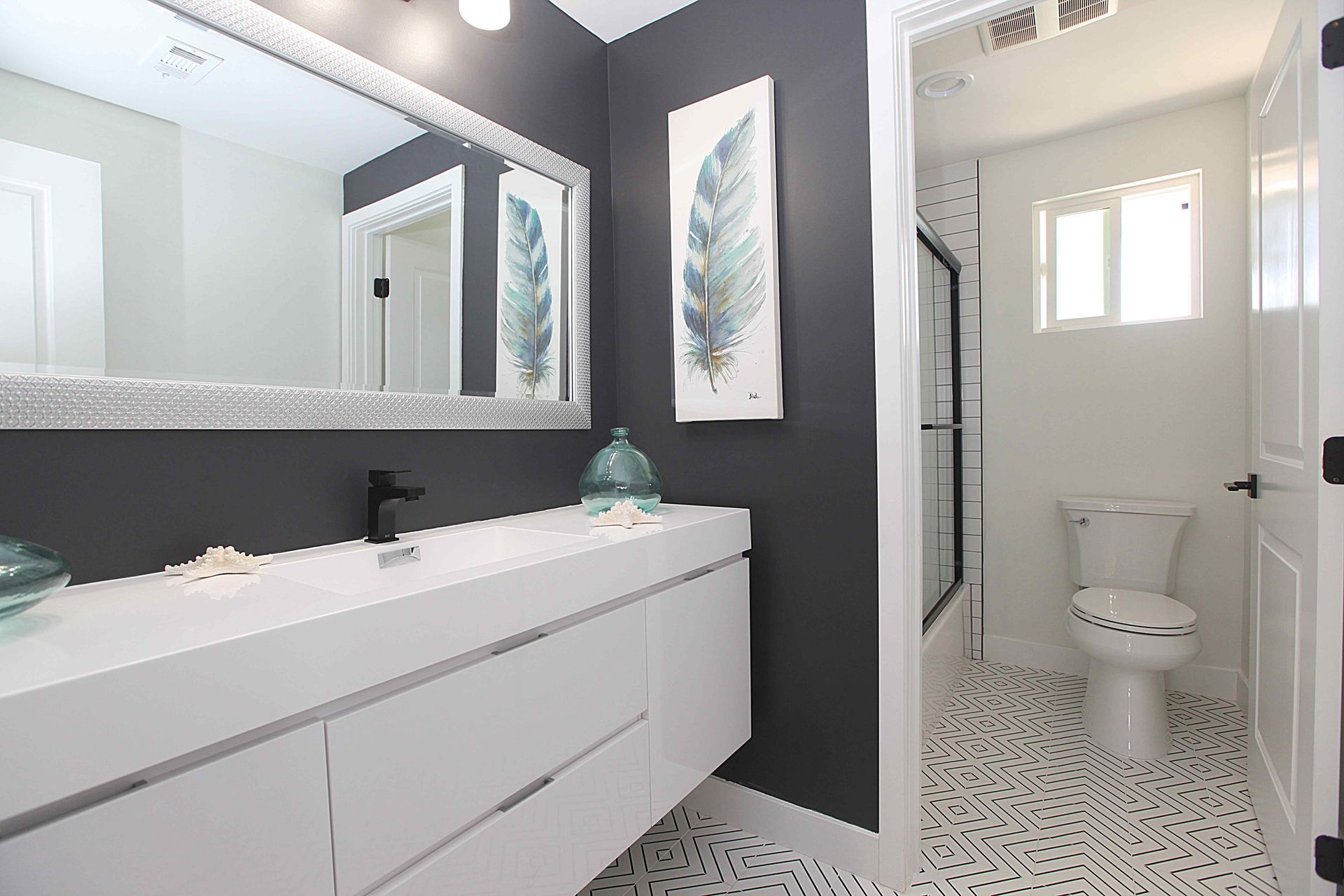 Modern bathroom with dark gray accent wall, white vanity, and patterned tile floor.