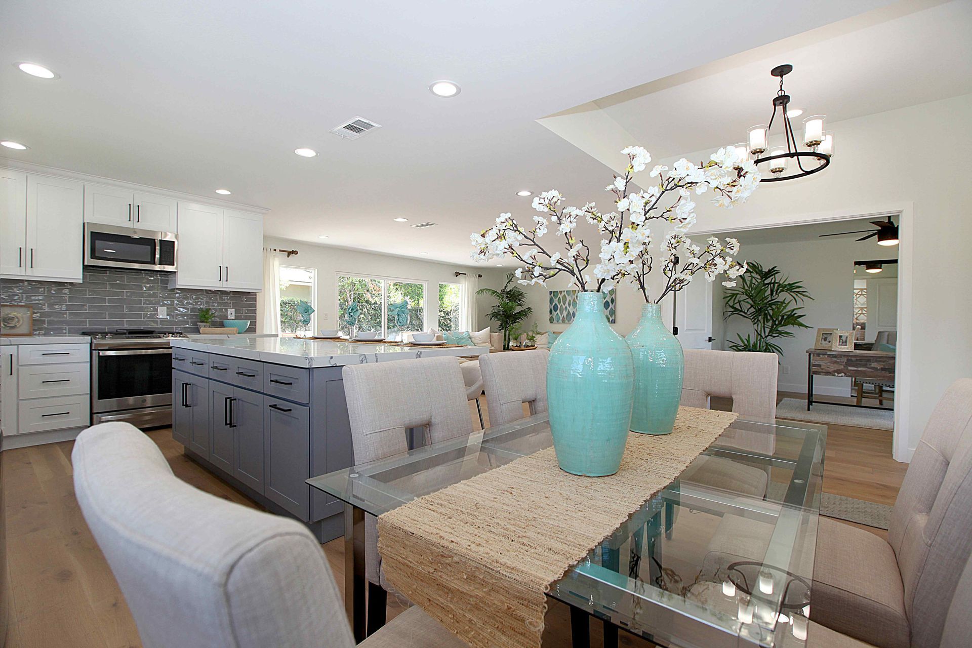 Modern kitchen and dining room with turquoise vases, gray island, and glass table.