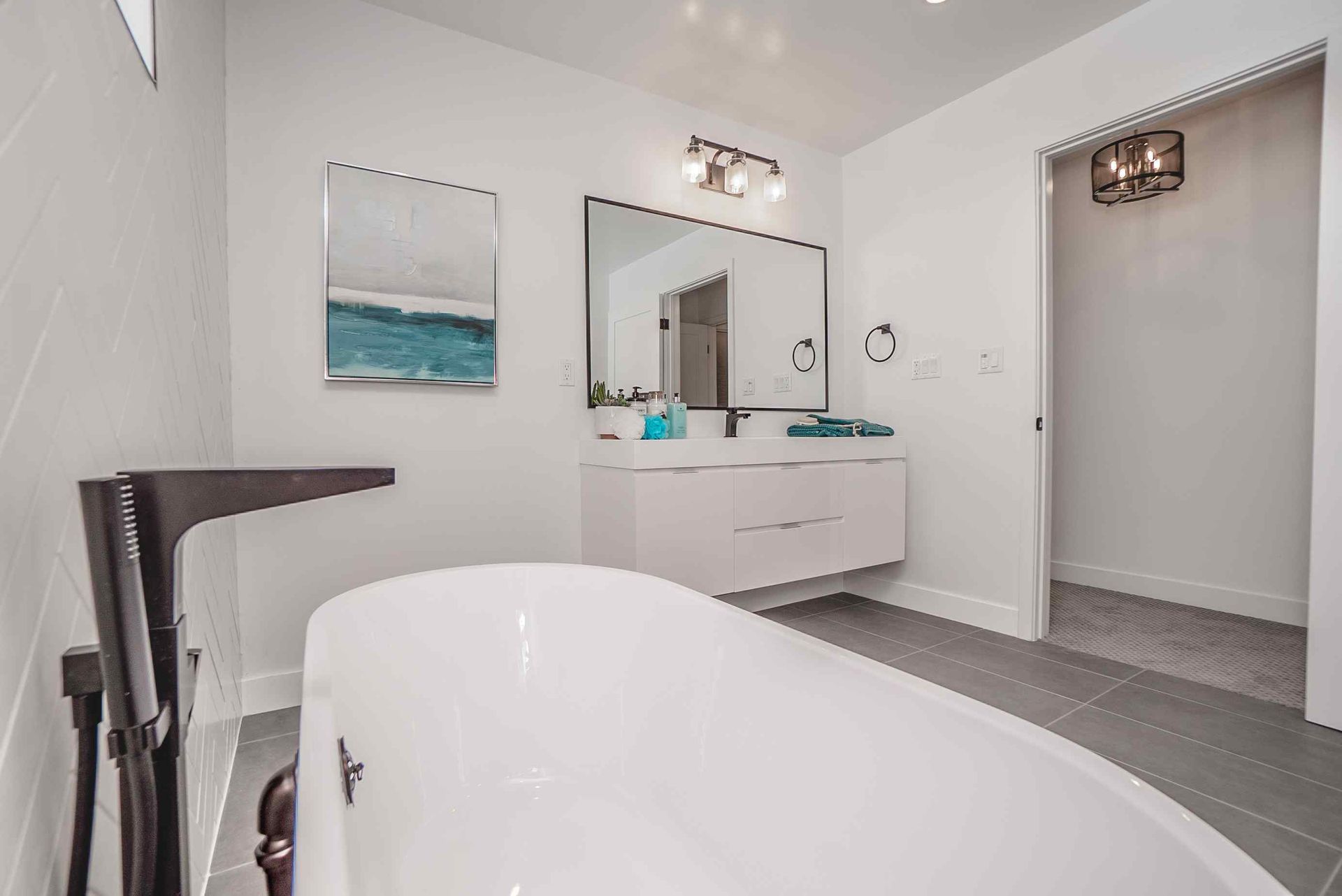 White bathroom with a freestanding tub, vanity, and doorway.