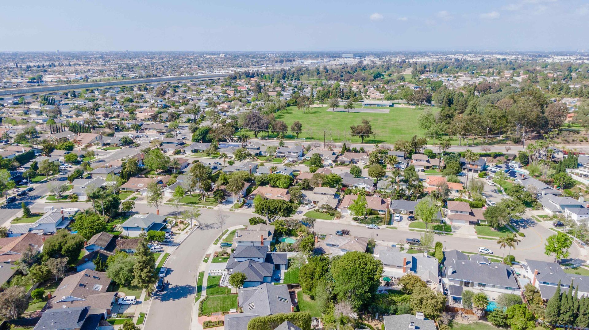 Aerial view of a residential neighborhood with houses, streets, and a park with a sports field.