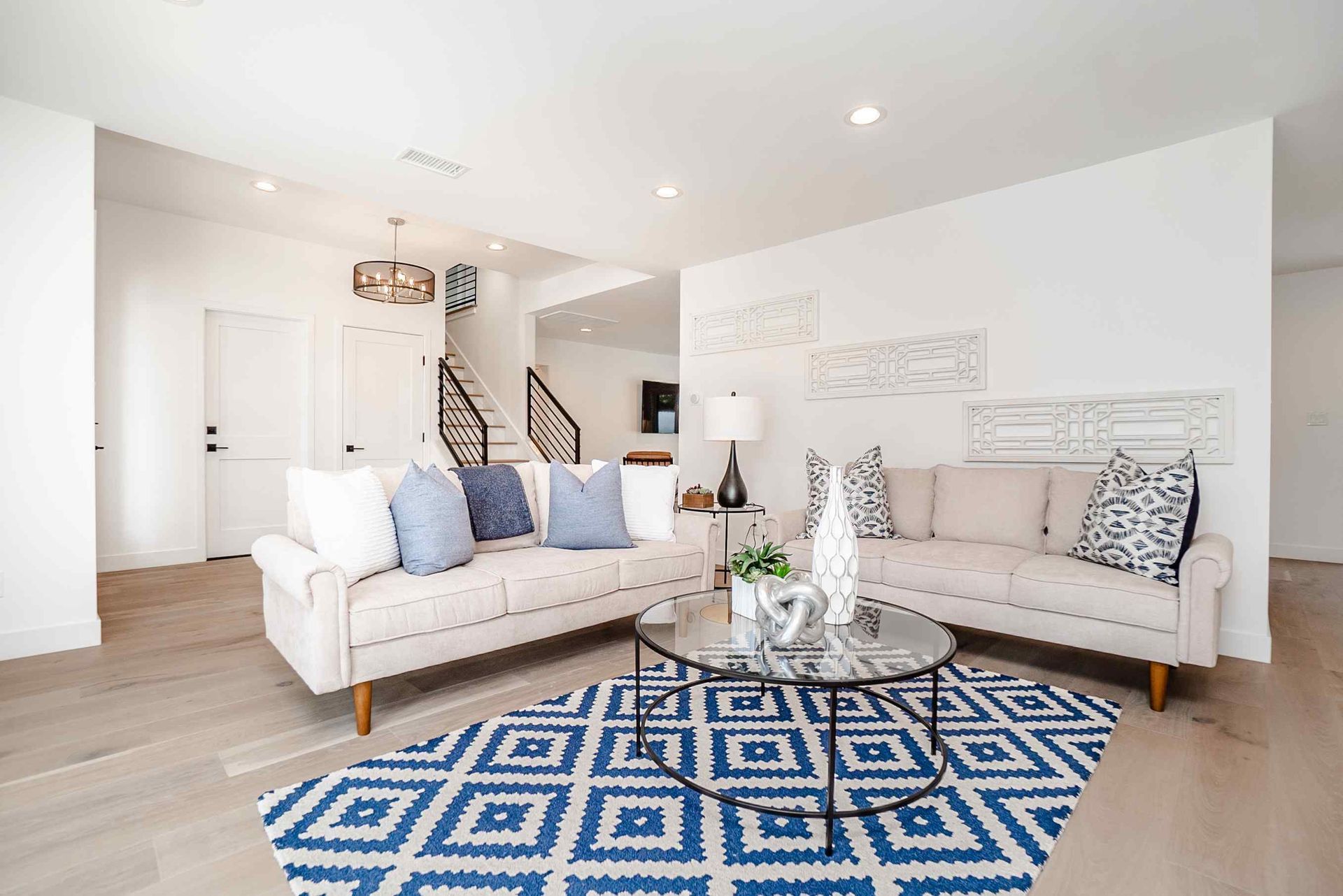 Living room with white sofas, blue rug, and modern decor.