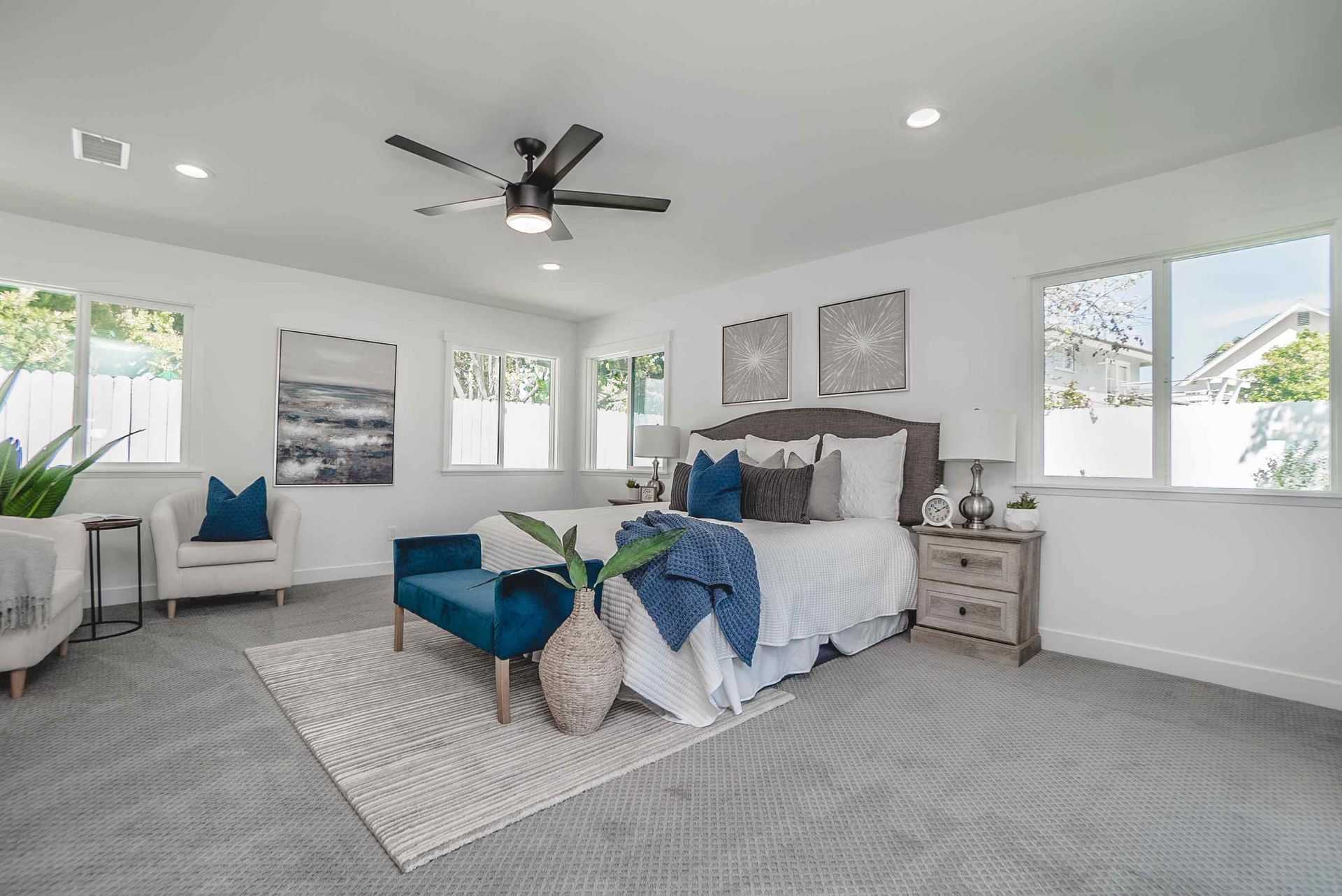 Spacious bedroom with white walls, a gray patterned rug, and blue accents around the bed.