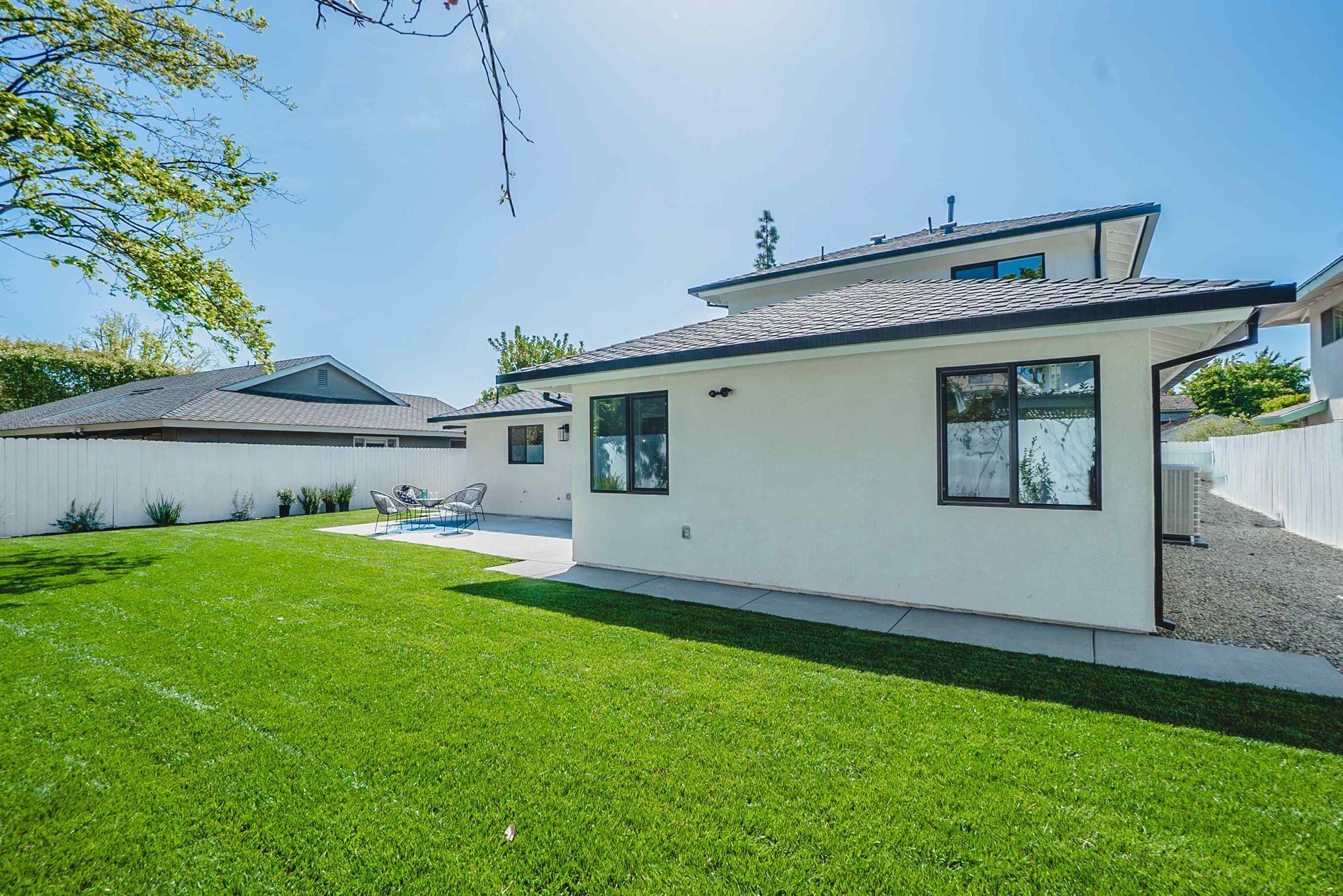 Exterior view of a white house with a green lawn and blue sky.