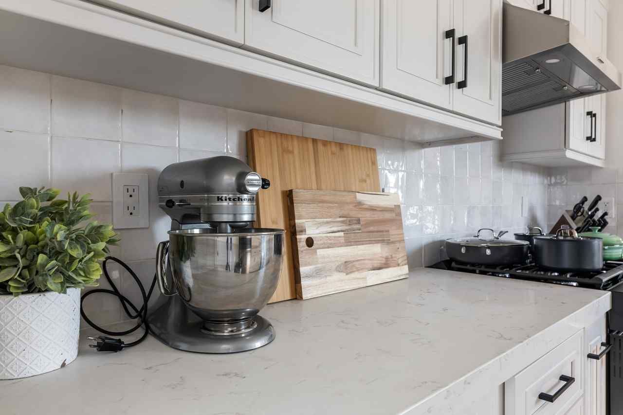 Kitchen counter with a silver mixer, cutting boards, and cooking pots.