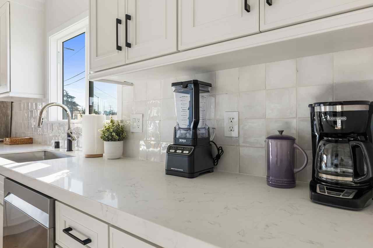 White kitchen with appliances on a light countertop; a coffee maker and blender are visible.