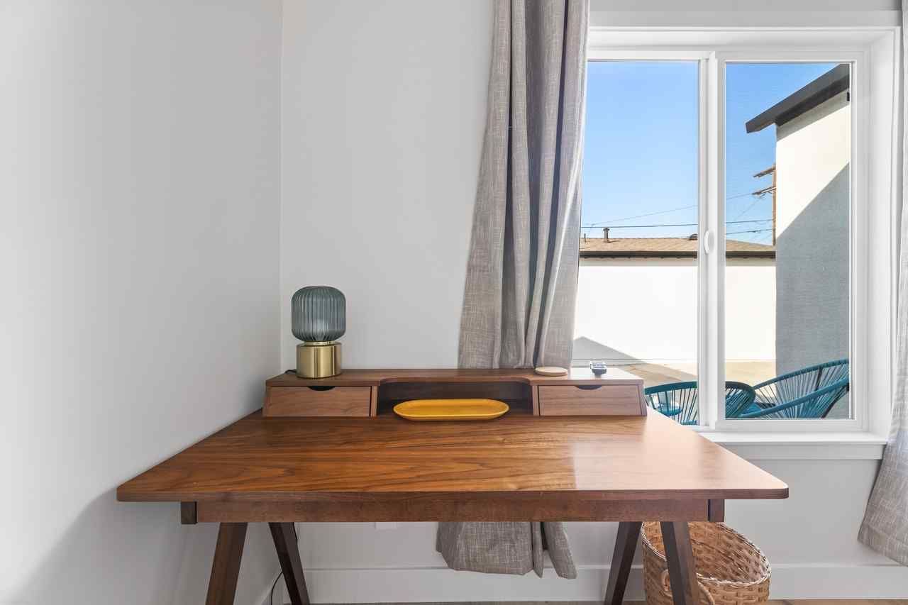 Wooden desk by a window, with lamp and drawers.