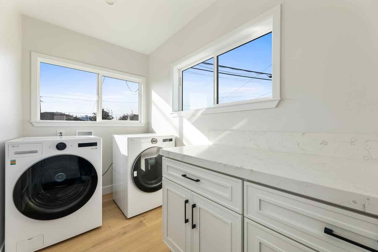 Laundry room with white cabinetry, windows, washer, and dryer; bright, sunny day.