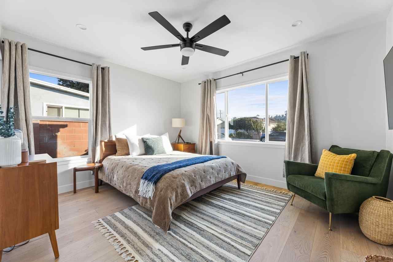 Bedroom with bed, armchair, windows, and neutral color scheme.