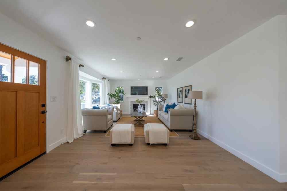 Spacious living room with neutral tones, two sofas, and a fireplace. Wooden floors and a large front door.